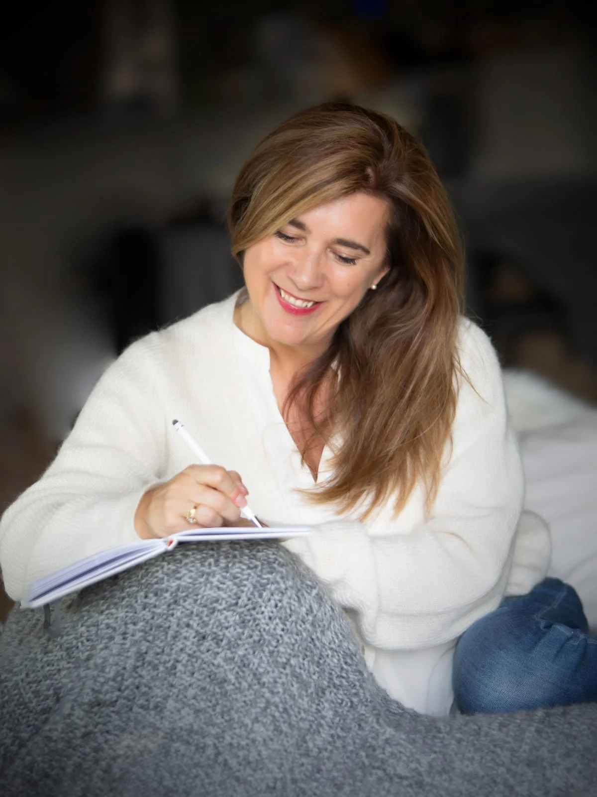 Johanne Côté prend des notes dans un carnet, assise dans un fauteuil