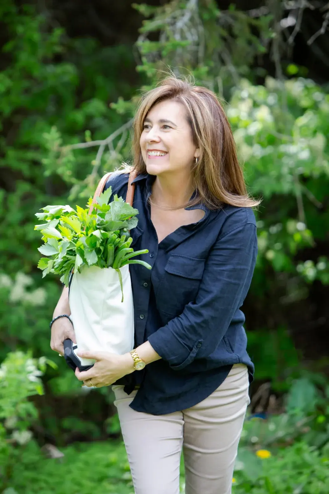 Johanne Côté dans le jardin, un sac de fines herbes fraîches dans les bras