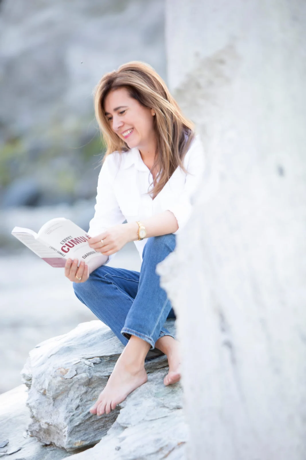 Johanne Côté lit le livre L'effet cumulé, assise sur un rocher
